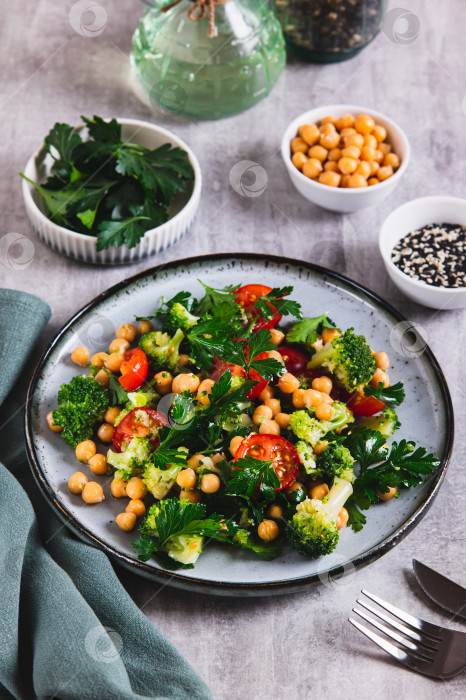 Скачать Смесь из нута, помидоров, брокколи и петрушки на тарелке, поданная на стол в вертикальном положении фотосток Ozero