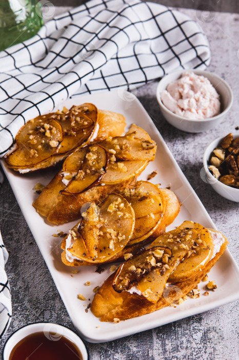 Скачать Аппетитные тосты со сливочным сыром, жареной грушей и медом на тарелке на столе в вертикальном положении фотосток Ozero