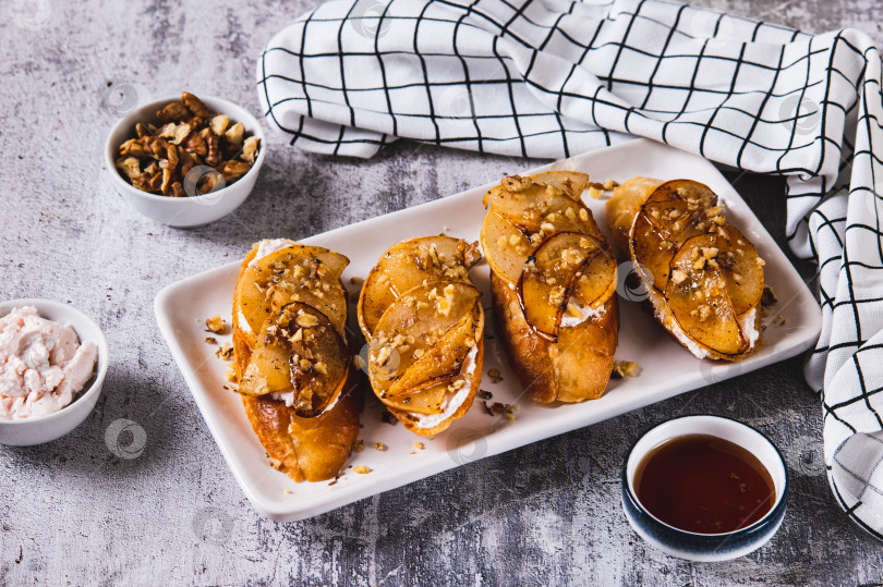 Скачать Вкусные тосты со сливочным сыром, жареной грушей и медом на тарелке на столе фотосток Ozero