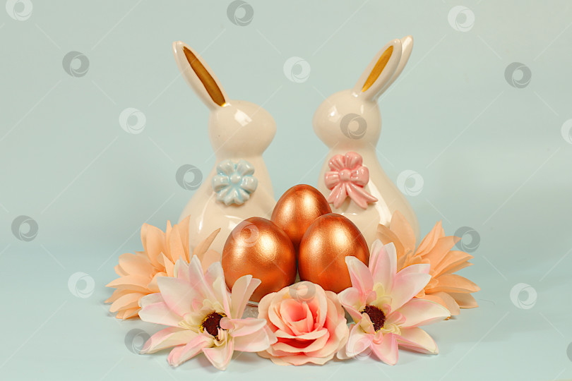 Скачать Концепция "Счастливой Пасхи". Абстрактная весенняя пасхальная композиция с золотыми крашеными яйцами, весенними лотосами и розами и праздничной поздравительной открыткой. Баннер на экране с местом для текста поздравления фотосток Ozero
