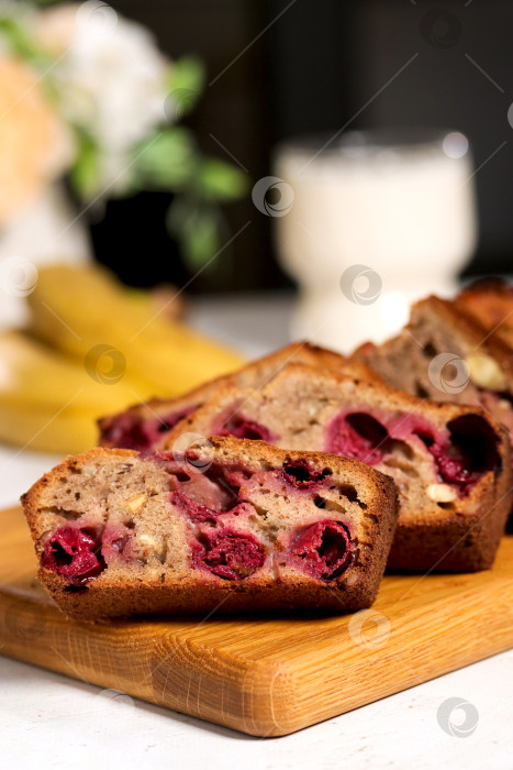 Скачать Свежеиспеченный банановый хлеб с вишней, нарезанный ломтиками, выложите на деревянную разделочную доску в уютной кухонной обстановке. Утренний завтрак со сладким хлебом из бананов и вишни фотосток Ozero