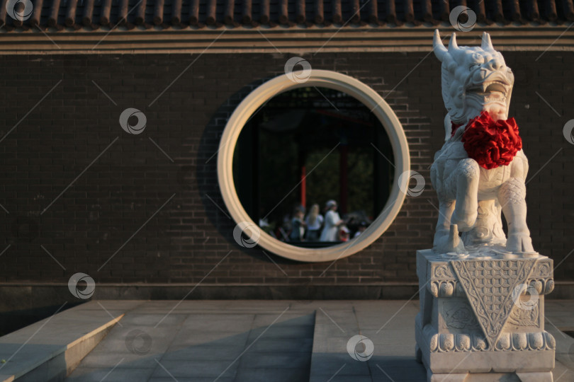 Скачать Китайский страж у круглого окна: гармония традиций и архитектуры фотосток Ozero