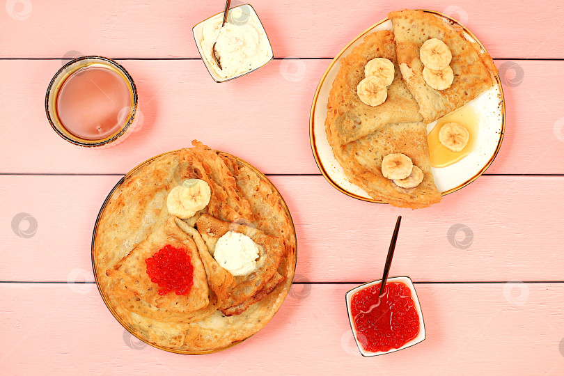 Скачать Вкусные русские блинчики с мягким сыром, бананами и красной икрой на кухонном столе. Полезный завтрак из свежих продуктов, масленичная концепция и традиционная русская кухня, особый акцент фотосток Ozero