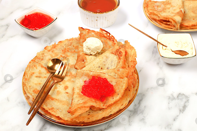 Скачать Вкусные русские блинчики с мягким сыром, бананами и красной икрой на мраморном столе. Полезный завтрак из свежих продуктов в стиле Масленицы и традиционной русской кухни фотосток Ozero