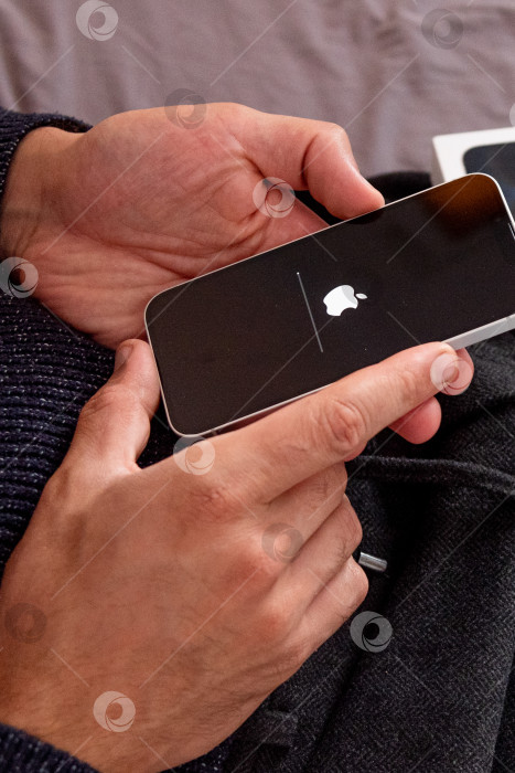 Скачать Бар, Черногория, 2 ноября 2025 года, Мужчина настраивает новый iPhone, первый запускаемый смартфон фотосток Ozero