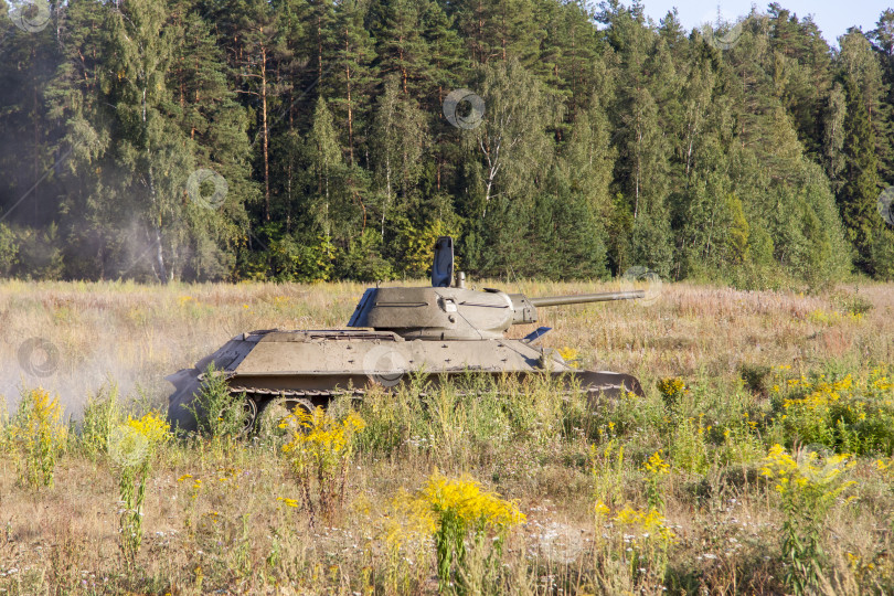 Скачать Москва, Россия, 2018-08-25, выставка военной техники, показ военной техники в действии. Военный танк в движении на фоне зеленых деревьев. фотосток Ozero