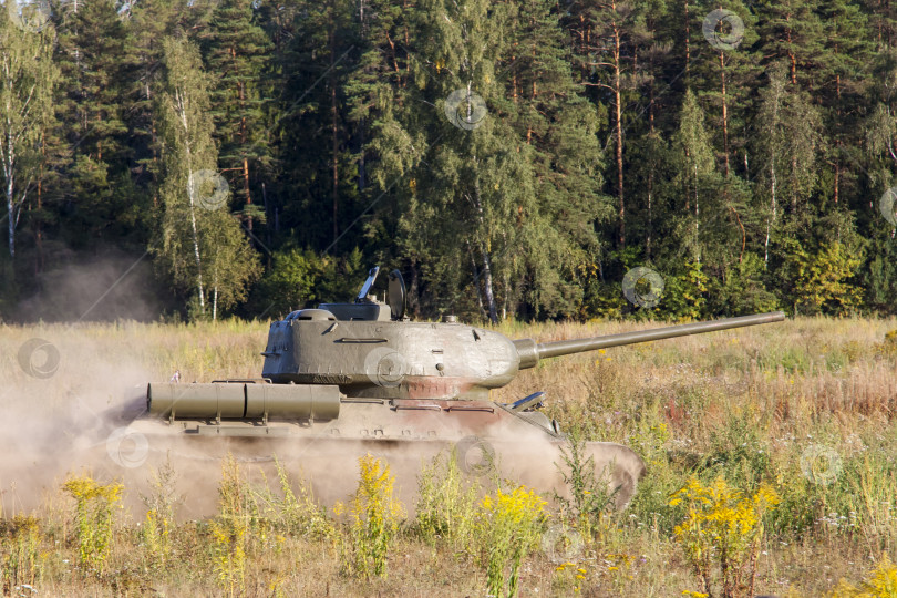 Скачать Москва, Россия, 2018-08-25, выставка военной техники, показ военной техники в действии. Военный танк в движении на фоне зеленых деревьев. фотосток Ozero