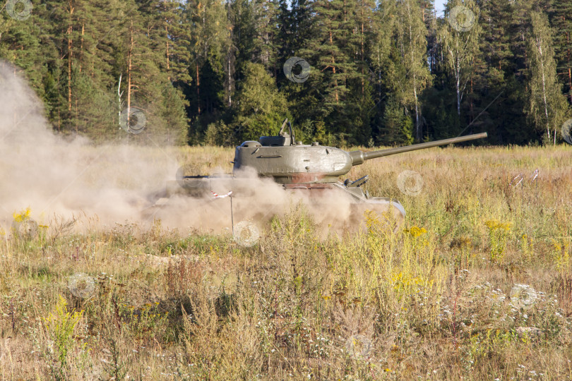 Скачать Москва, Россия, 2018-08-25, выставка военной техники, показ военной техники в действии. Военный танк в движении на фоне зеленых деревьев. фотосток Ozero