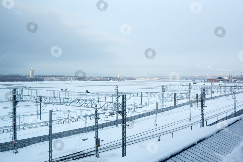 Скачать Железнодорожная станция у замерзшей реки на фоне города. Зимний пейзаж. фотосток Ozero