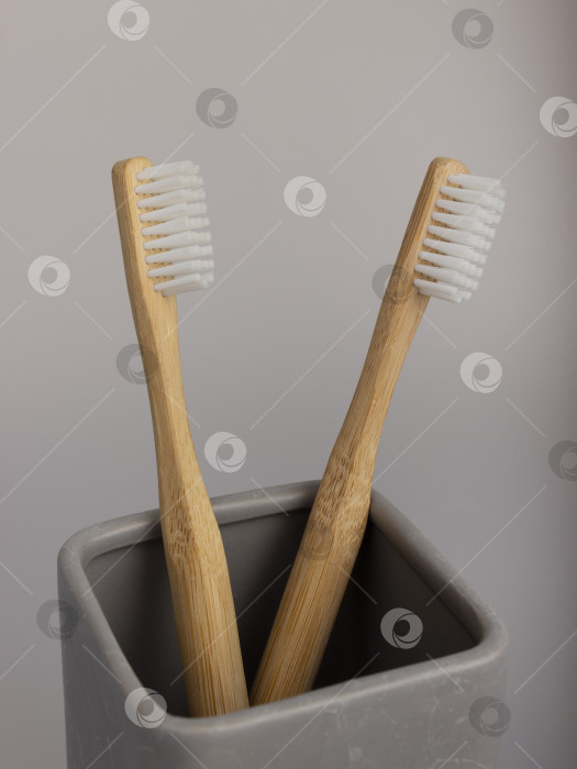 Скачать натуральная экологичная зубная щетка с деревянной ручкой из бамбука в керамической чашке фотосток Ozero