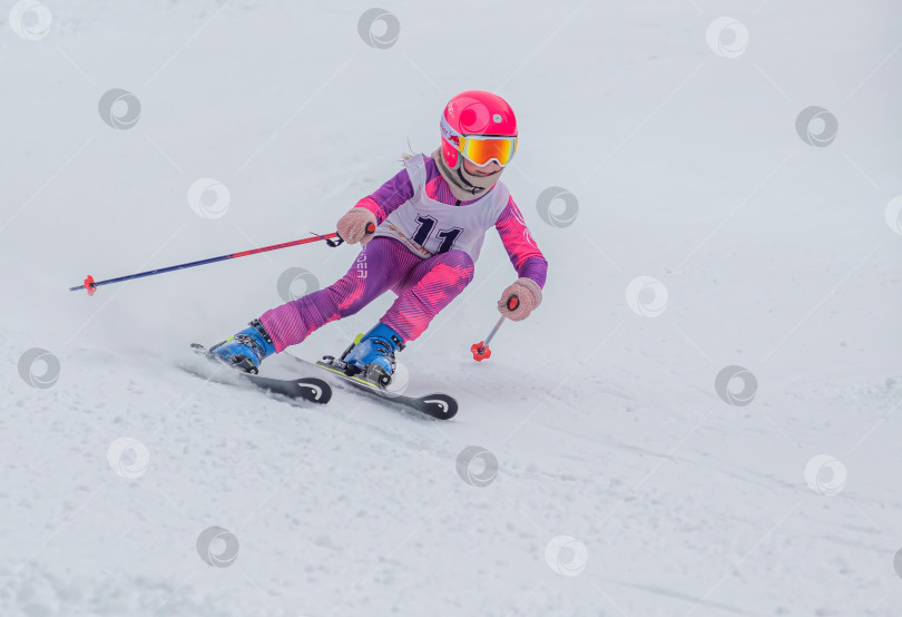 Скачать Россия, Красноярск 25 февраля 2025г. Девочка лыжница, спускается на лыжах по снежному склону. фотосток Ozero