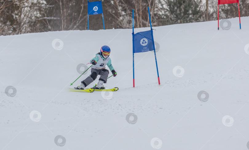 Скачать Россия, Красноярск 25 февраля 2025г. Мальчик лыжник, спускается на лыжах по снежному склону. фотосток Ozero