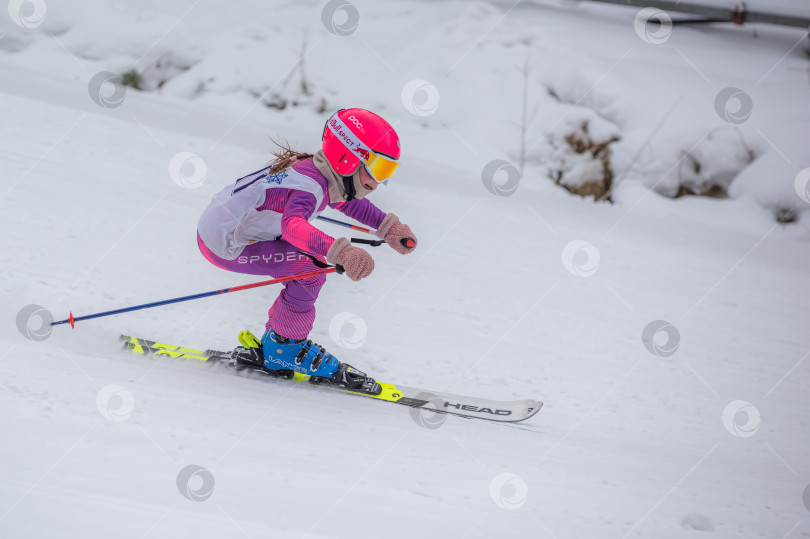 Скачать Россия, Красноярск 25 февраля 2025г. Девочка лыжница, спускается на лыжах по снежному склону. фотосток Ozero