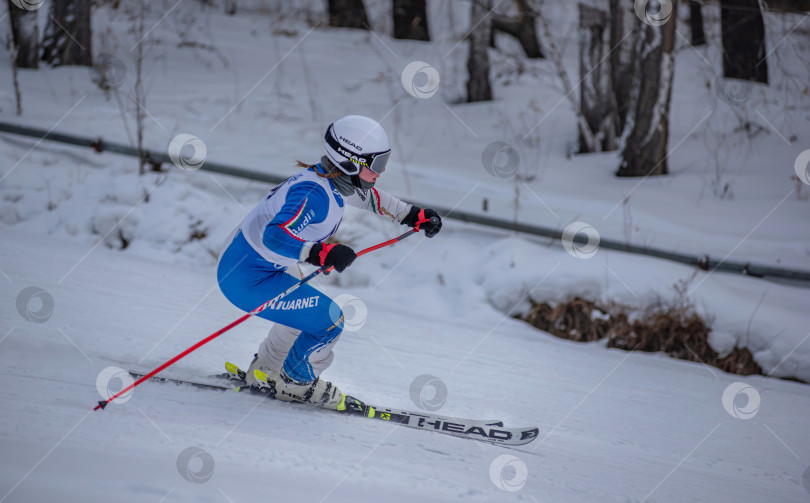 Скачать Россия, Красноярск 25 февраля 2025г. Девочка лыжница, спускается на лыжах по снежному склону. фотосток Ozero