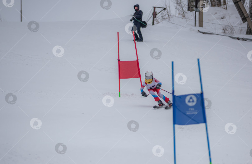 Скачать Россия, Красноярск 25 февраля 2025г. Мальчик лыжник, спускается на лыжах по снежному склону. фотосток Ozero