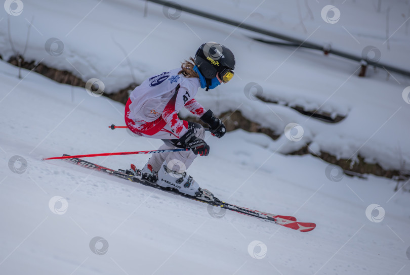 Скачать Россия, Красноярск 25 февраля 2025г. Девочка лыжница, спускается на лыжах по снежному склону. фотосток Ozero