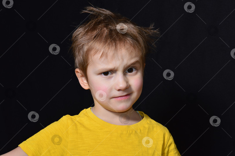 Скачать Эмоциональный мальчик с карими глазами в желтой футболке на черном фоне фотосток Ozero