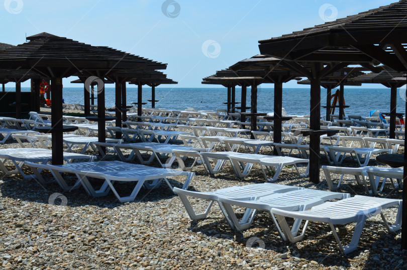 Скачать Шезлонги белого цвета и черные деревянные навесы от солнца фотосток Ozero