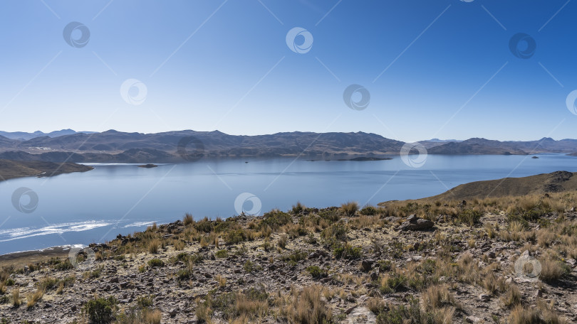 Скачать Красивое голубое альпийское озеро. На берегу, среди сухой травы, разбросаны валуны фотосток Ozero