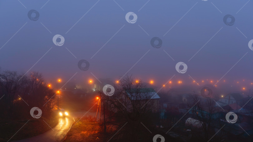 Скачать Ночная дорога в тумане, освещенная уличными фонарями фотосток Ozero