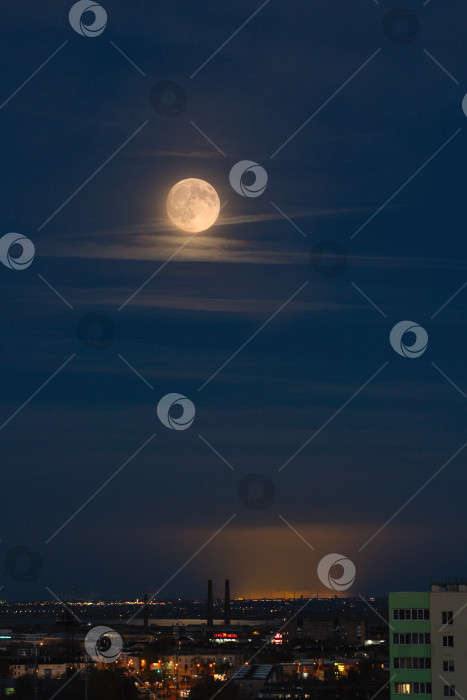 Скачать Полная луна поднимается над освещенным городским пейзажем фотосток Ozero