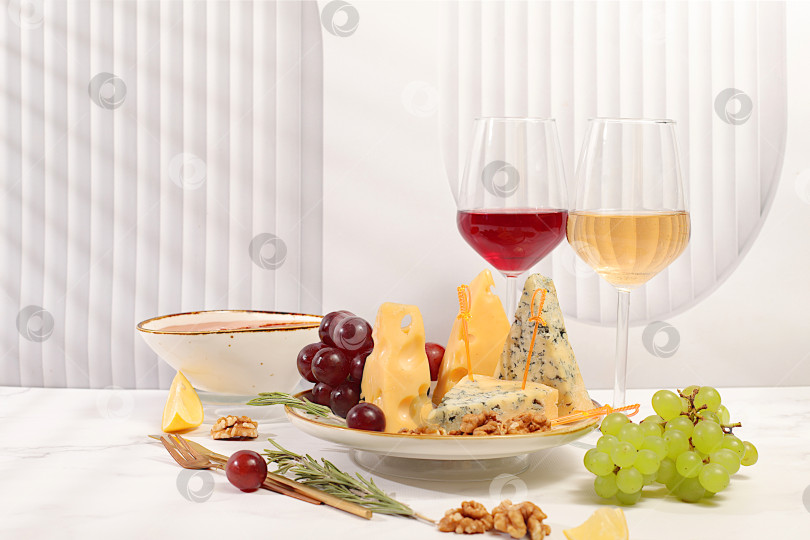 Скачать Натюрморт с изысканным голубым сыром, пармезаном, виноградом, медом, орехами, розмарином и вином. Сырное ассорти с сезонными винными закусками, концепция итальянской кухни и меню ресторана и кафе. фотосток Ozero