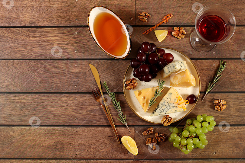 Скачать Натюрморт с изысканным голубым сыром, пармезаном, виноградом, медом, орехами, розмарином и вином. Вид сверху на сырную тарелку с сезонными винными закусками, концепция итальянской кухни, меню ресторана и кафе. фотосток Ozero