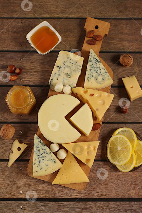 Скачать Натюрморт с изысканным голубым сыром, пармезаном, виноградом, медом, орехами, розмарином, лимоном и грецкими орехами. Сырное ассорти с сезонными винными закусками, концепция итальянской кухни и ресторанное меню. фотосток Ozero