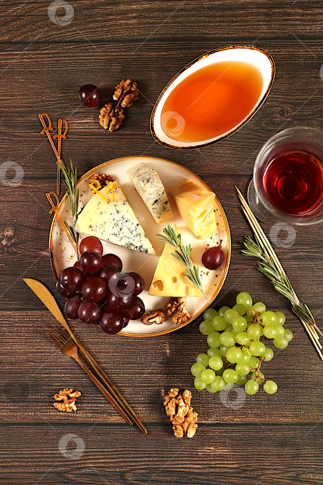 Скачать Натюрморт с изысканным голубым сыром, пармезаном, виноградом, медом, орехами, розмарином и вином. Вид сверху на сырную тарелку с сезонными винными закусками, концепция итальянской кухни, меню ресторана и кафе. фотосток Ozero