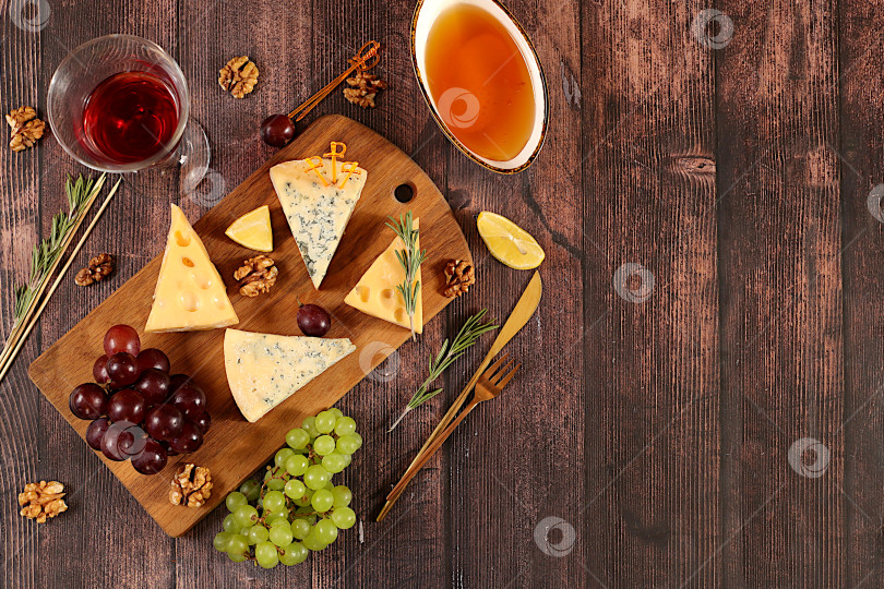 Скачать Натюрморт с изысканным голубым сыром, пармезаном, виноградом, медом, орехами, розмарином и вином. Вид сверху на сырную тарелку с сезонными винными закусками, концепция итальянской кухни, меню ресторана и кафе. фотосток Ozero