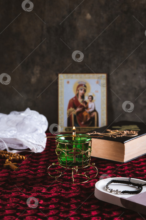Скачать Горящая православная лампада, Библия, крест на цепочке и икона на столе в вертикальном положении фотосток Ozero