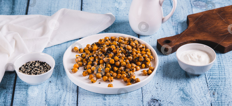 Скачать Вкусный запеченный нут с укропом и кунжутом на тарелке на столе - веб-баннер фотосток Ozero