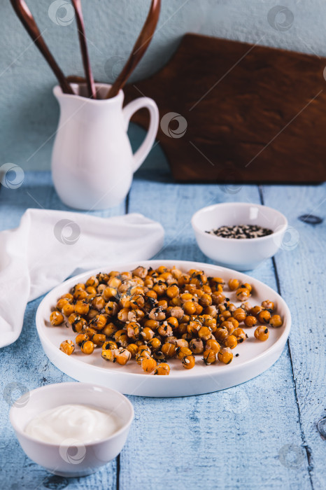 Скачать Вкусный запеченный нут с укропом и кунжутом на тарелке на столе в вертикальном положении фотосток Ozero