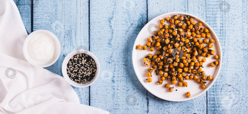 Скачать Аппетитный запеченный нут с кунжутом и зеленью на тарелке вид сверху веб-баннер фотосток Ozero