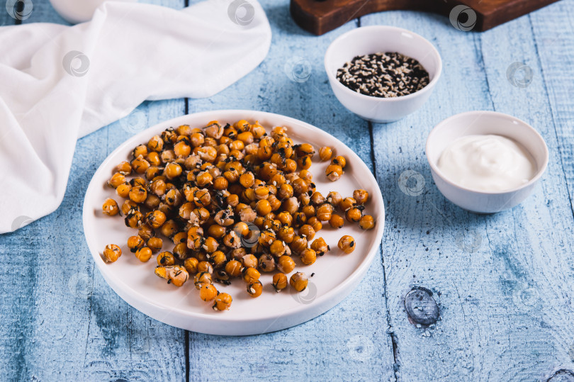 Скачать Аппетитный запеченный нут с кунжутом и зеленью на тарелке на столе фотосток Ozero