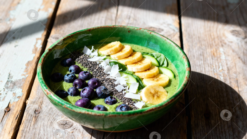 Скачать Большой зеленый союз с бананом, черной, огурцом и семенами чиа в зеленой чаше на деревянном столе фотосток Ozero