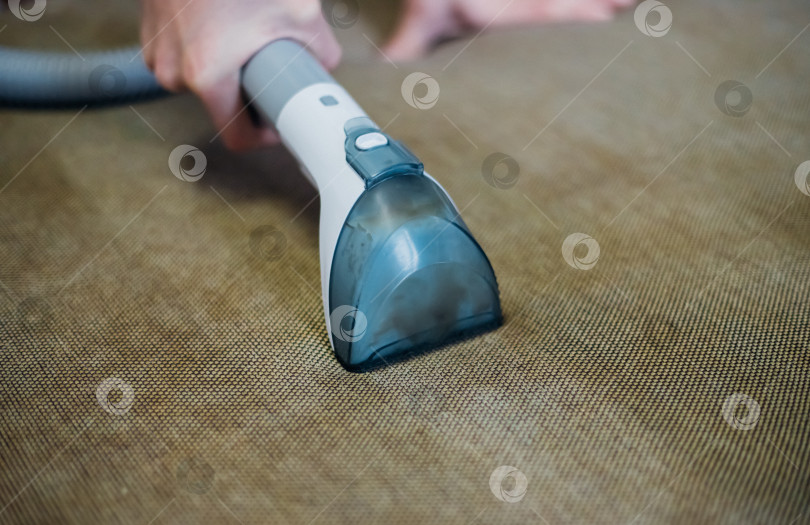 Скачать Крупный план влажной уборки грязным диваном с помощью сухого пылесоса. Домашняя уборка. фотосток Ozero