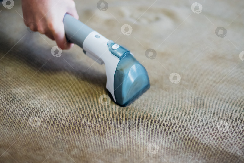 Скачать Крупный план влажной уборки грязным диваном с помощью сухого пылесоса. Домашняя уборка. фотосток Ozero