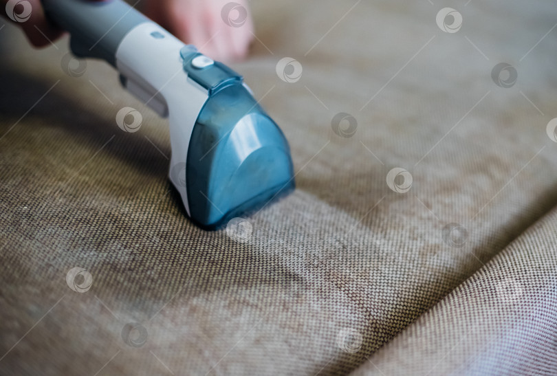 Скачать Крупный план влажной уборки грязным диваном с помощью сухого пылесоса. Домашняя уборка. фотосток Ozero