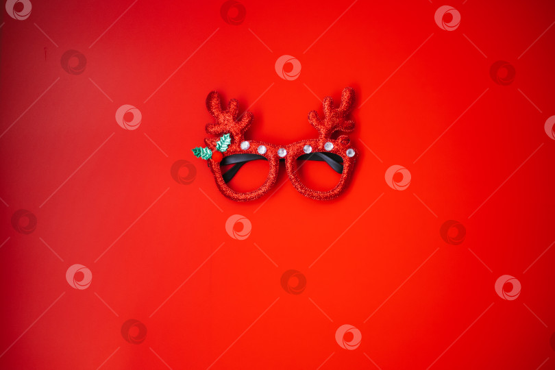 Скачать Рождественские маскарадные очки с оленьими рогами на красном фоне. Концепция рождественской вечеринки. Веселый праздник. Украшение для детей и взрослых. фотосток Ozero