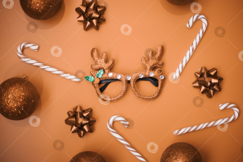 Скачать Рождественские бокалы-маскарады с оленьими рогами, шариками, леденцами на палочке на золотистом фоне. Концепция рождественской вечеринки. Веселый праздник. Украшение для детей и взрослых. фотосток Ozero