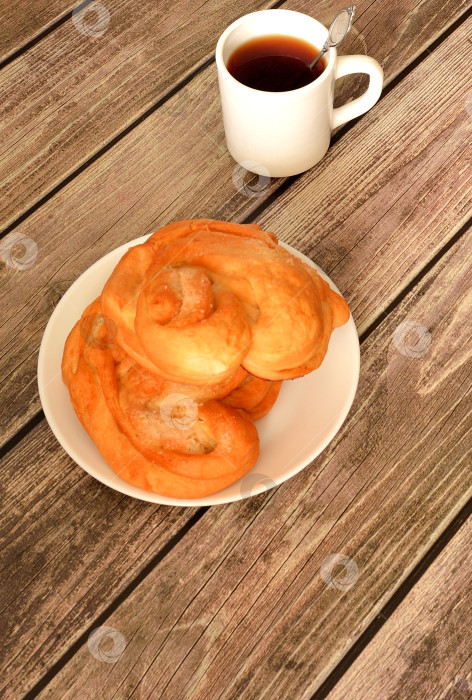 Скачать Два сахарных кренделька в круглой тарелке на деревянном столе, чашка чая рядом. фотосток Ozero