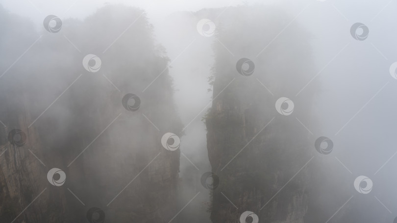 Скачать Высокие каменные столбы окутаны туманом и облаками. фотосток Ozero