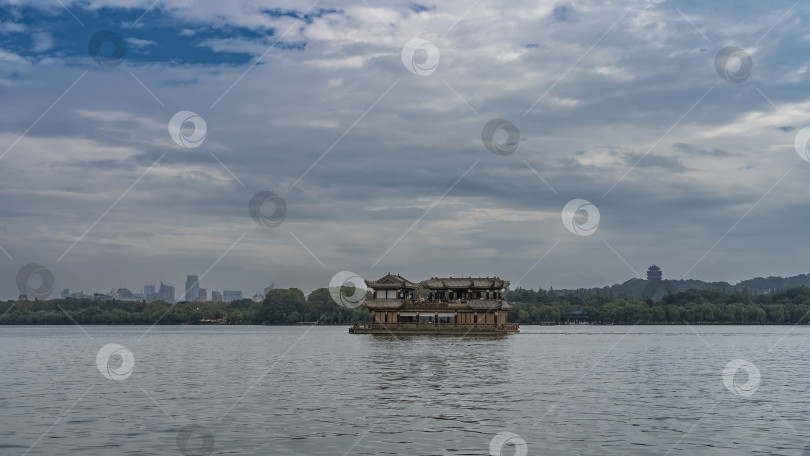 Скачать Красивая двухпалубная китайская лодка плывет по живописному озеру. фотосток Ozero