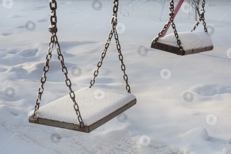 Скачать Две пустые деревянные качели, подвешенные на железных цепях в лютый зимний холод. фотосток Ozero