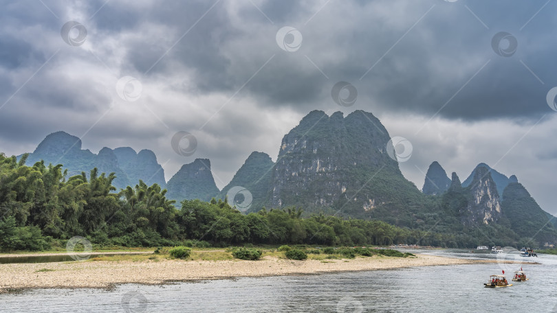 Скачать По живописной реке плывут туристические суда и бамбуковые плоты. фотосток Ozero