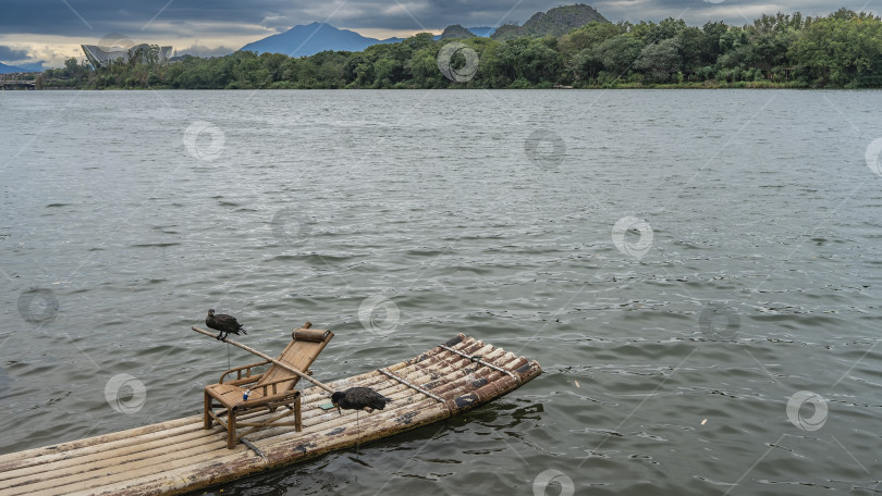 Скачать Живописная река. Деревянный стул установлен на бамбуковом плоту. фотосток Ozero