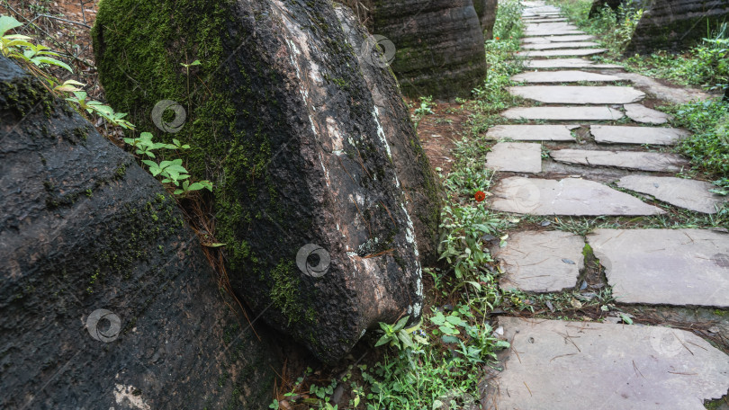 Скачать Пешеходная дорожка из каменных секций проходит между живописными валунами. фотосток Ozero