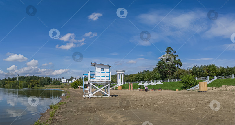 Скачать Россия,город Железногорск Красноярский Край, 08 июля 2025 год. Пляж с вышкой спасателя. Вокруг зелёная трава и деревья. Небо голубое с облаками. фотосток Ozero