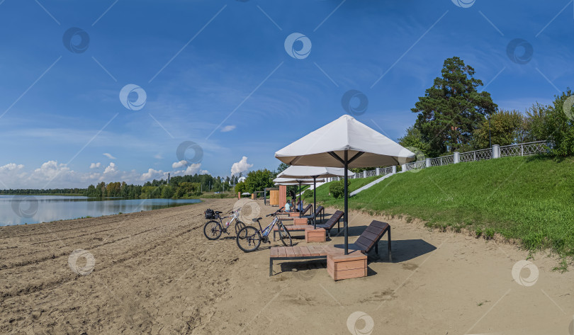 Скачать Россия,город Железногорск Красноярский Край, 08 июля 2025 год. Пляж,  шезлонги под зонтом, велосипед, голубое небо с облаками, фотосток Ozero